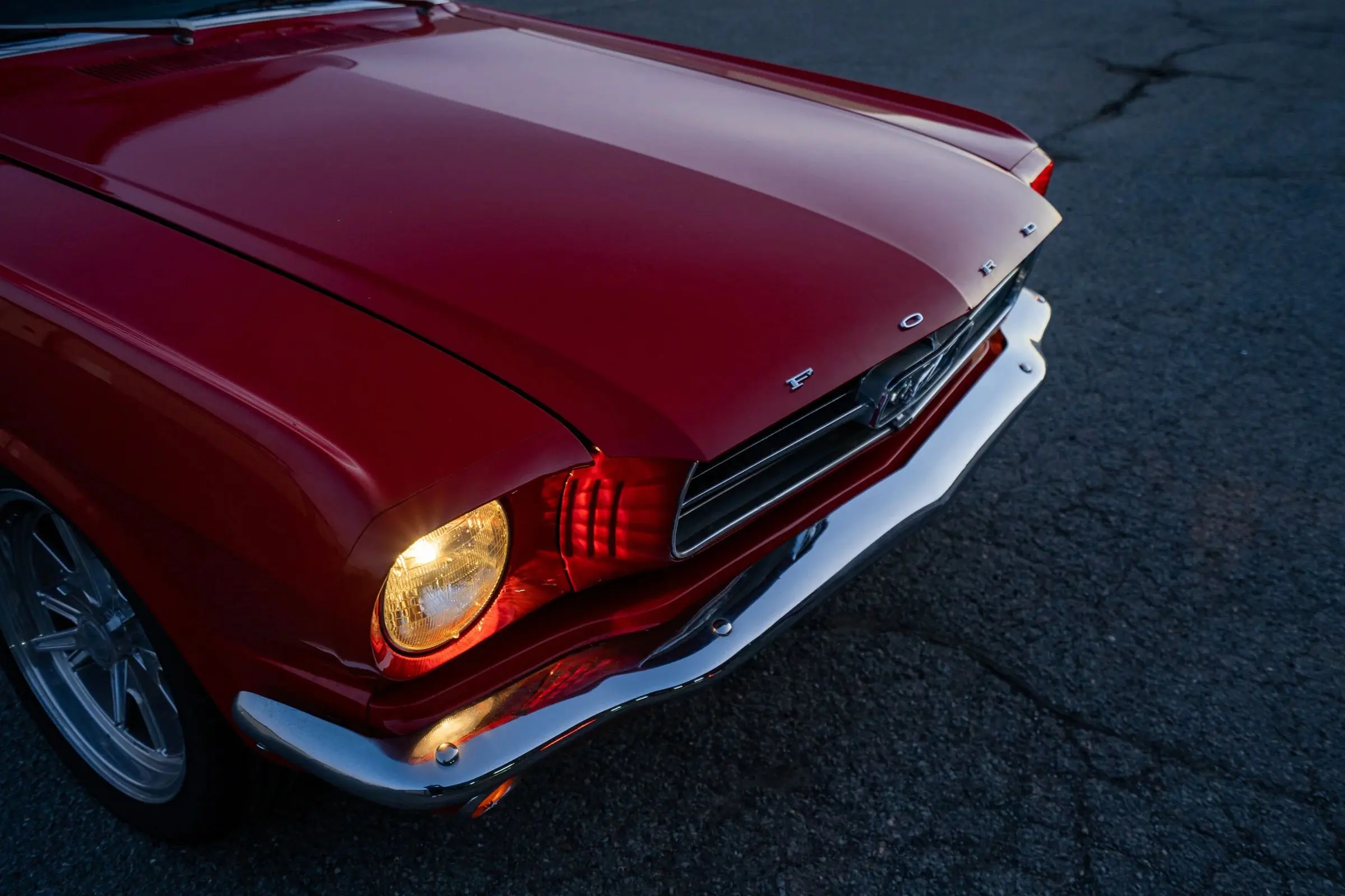 A red 1964 Ford Mustang shot low from the front at dusk
